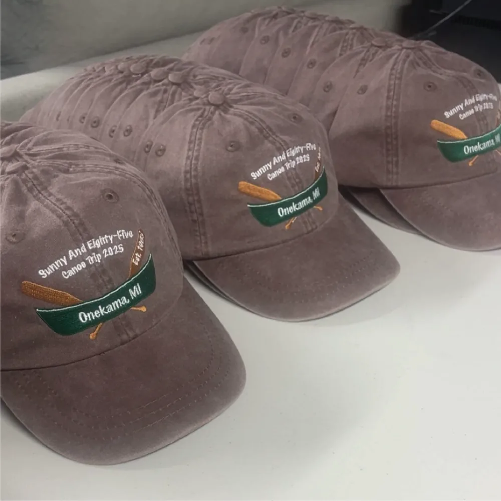 Four washed brown dad hats with embroidered canoe and Onekama, MI design